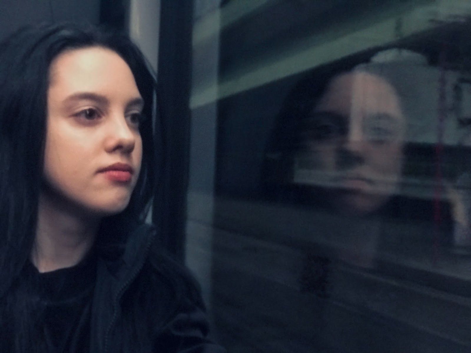 Девушка смотрит в окно с мечтательной улыбкой — delulu-фантазии

