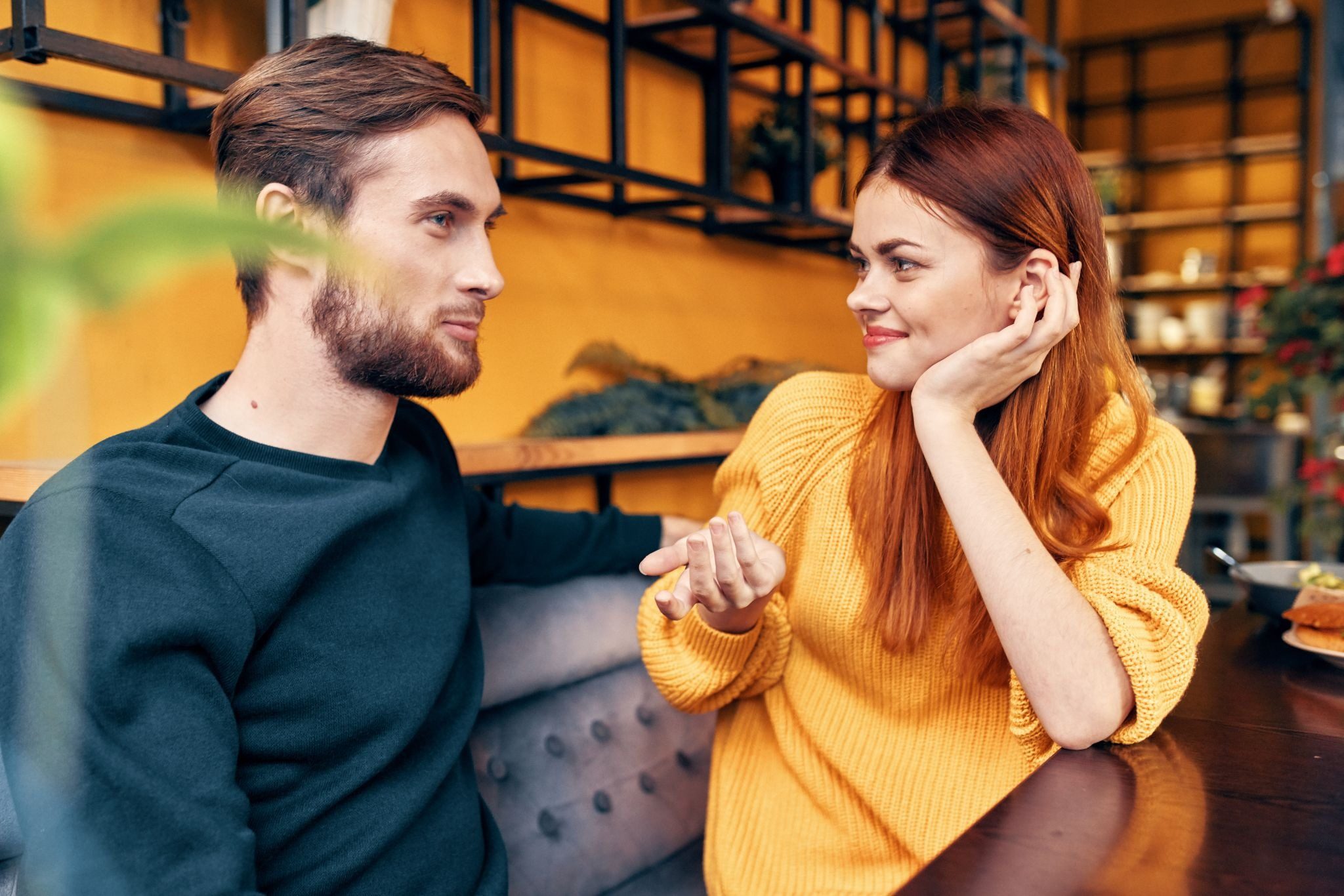 Смущённая девушка сидит напротив парня и не решается признаться в симпатии