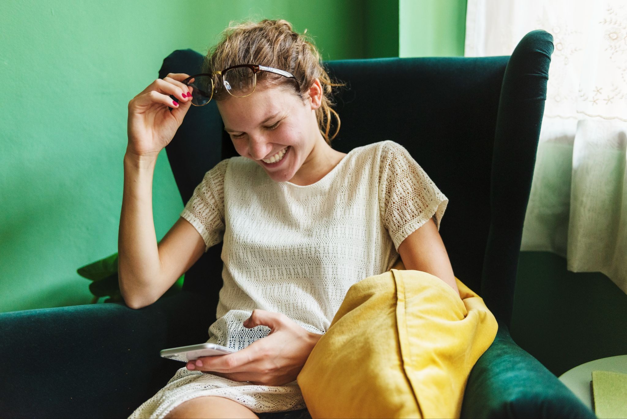 Девушка улыбается читая необычное первое сообщение от парня в мессенджере