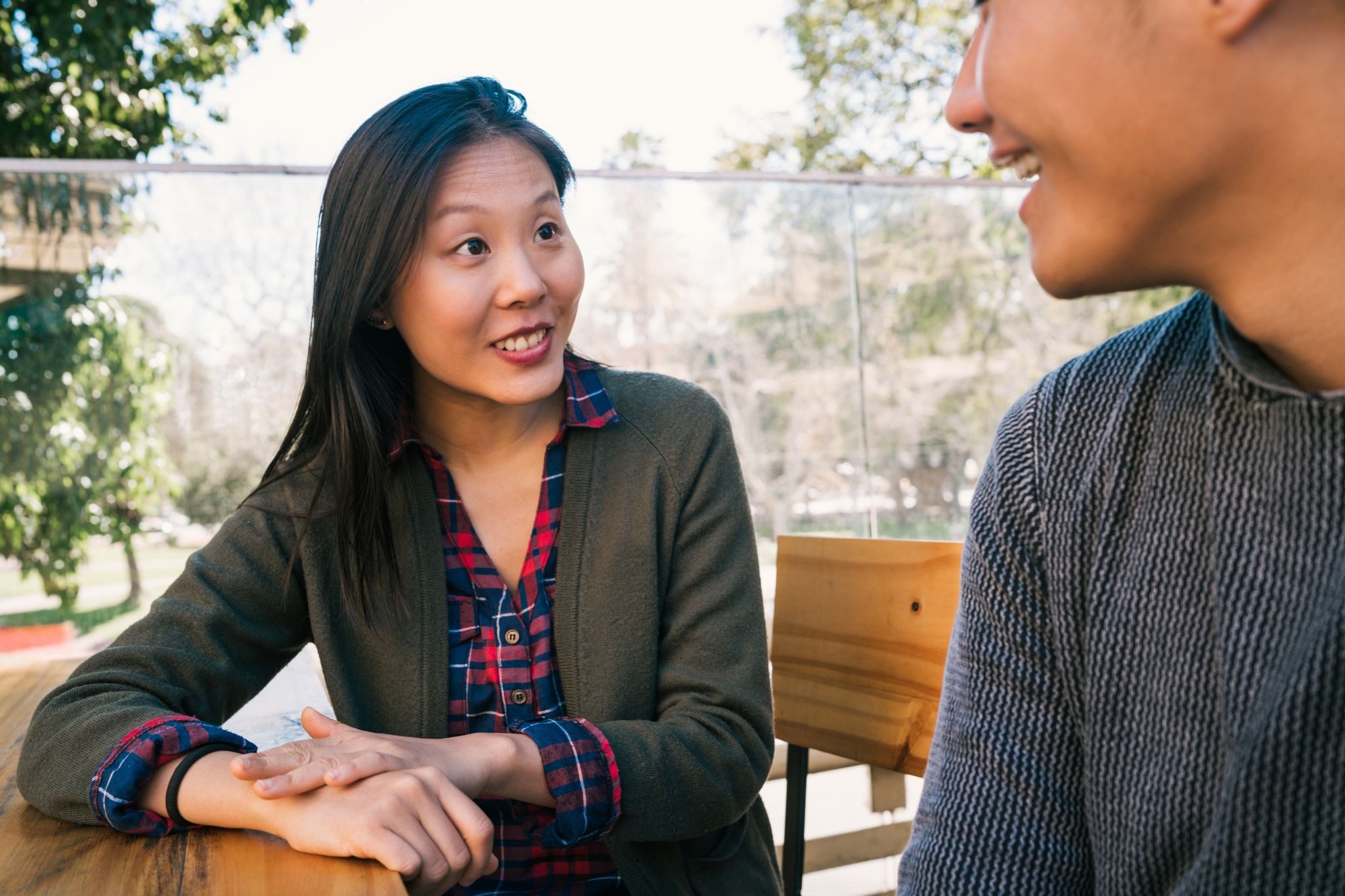 Мужчина и кореянка сидят в кофейне и разговаривают на свидании