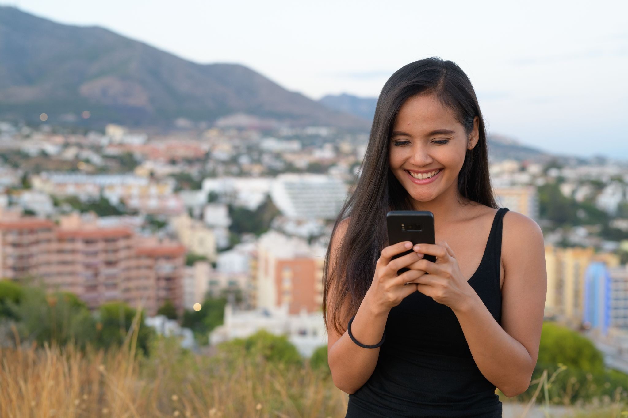 Японка с ухоженной кожей и макияжем смотрит в камеру телефона