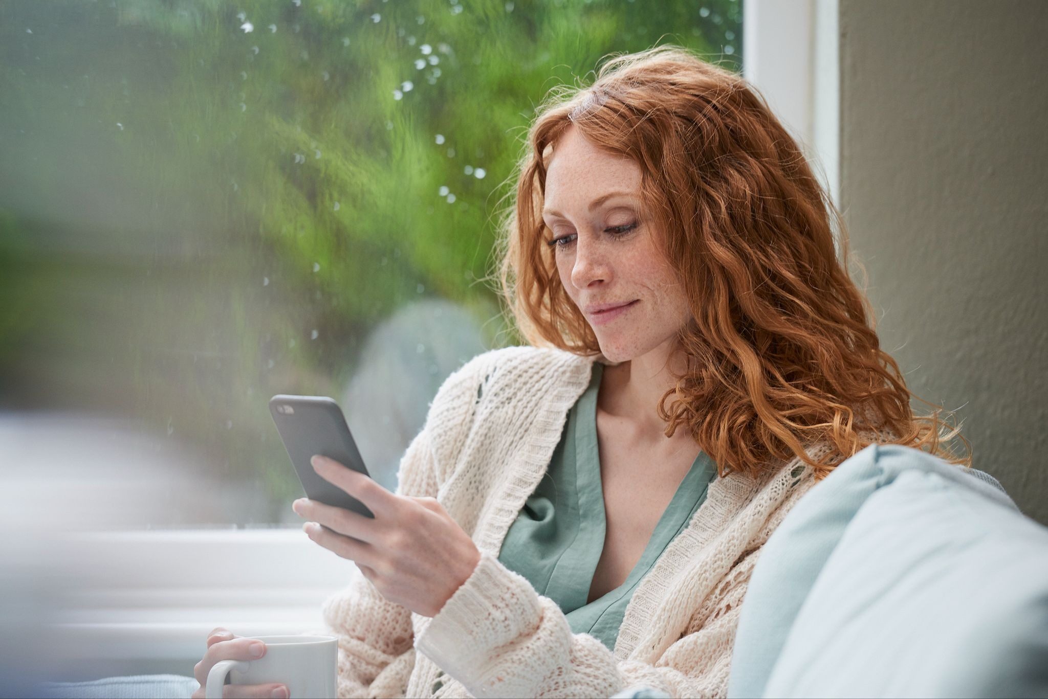 Девушка улыбается читая интересное сообщение от парня в переписке