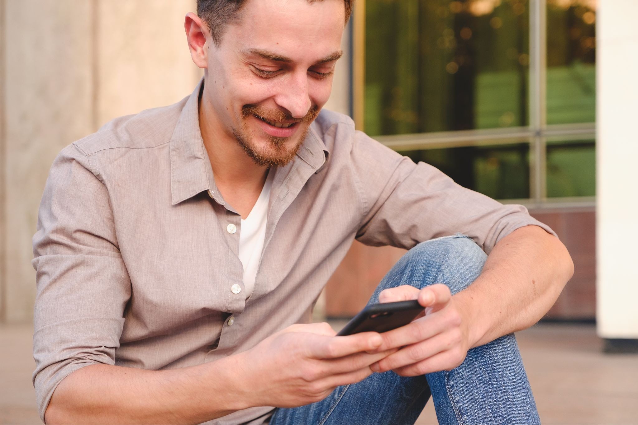 Парень сидит с телефоном и придумывает что написать девушке в интернете