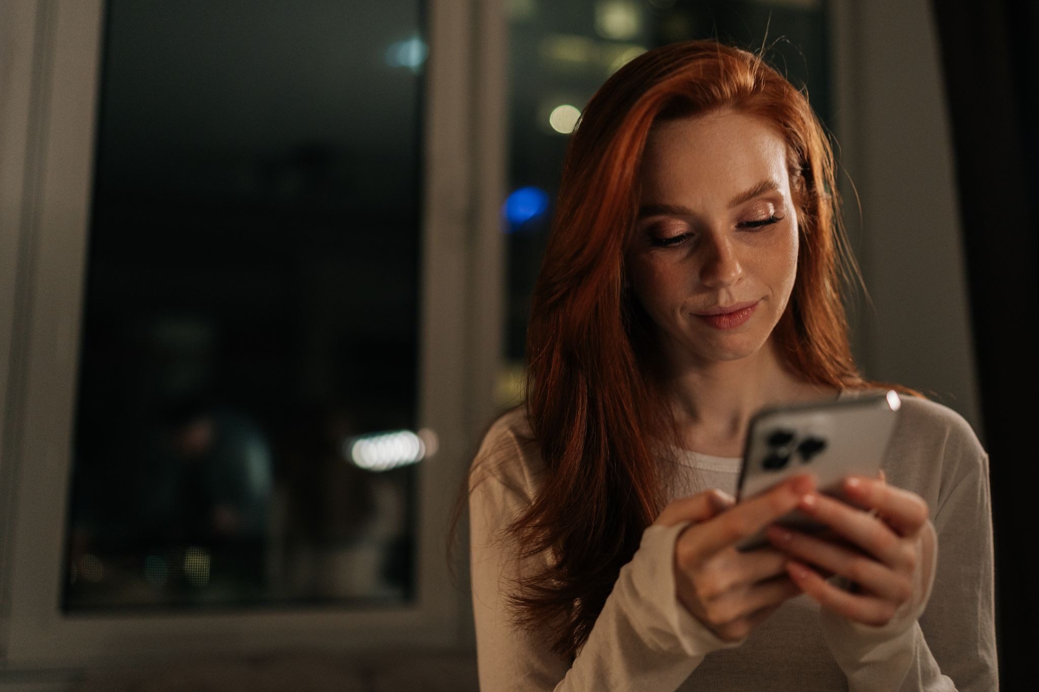 девушка улыбается, читая сообщение от парня