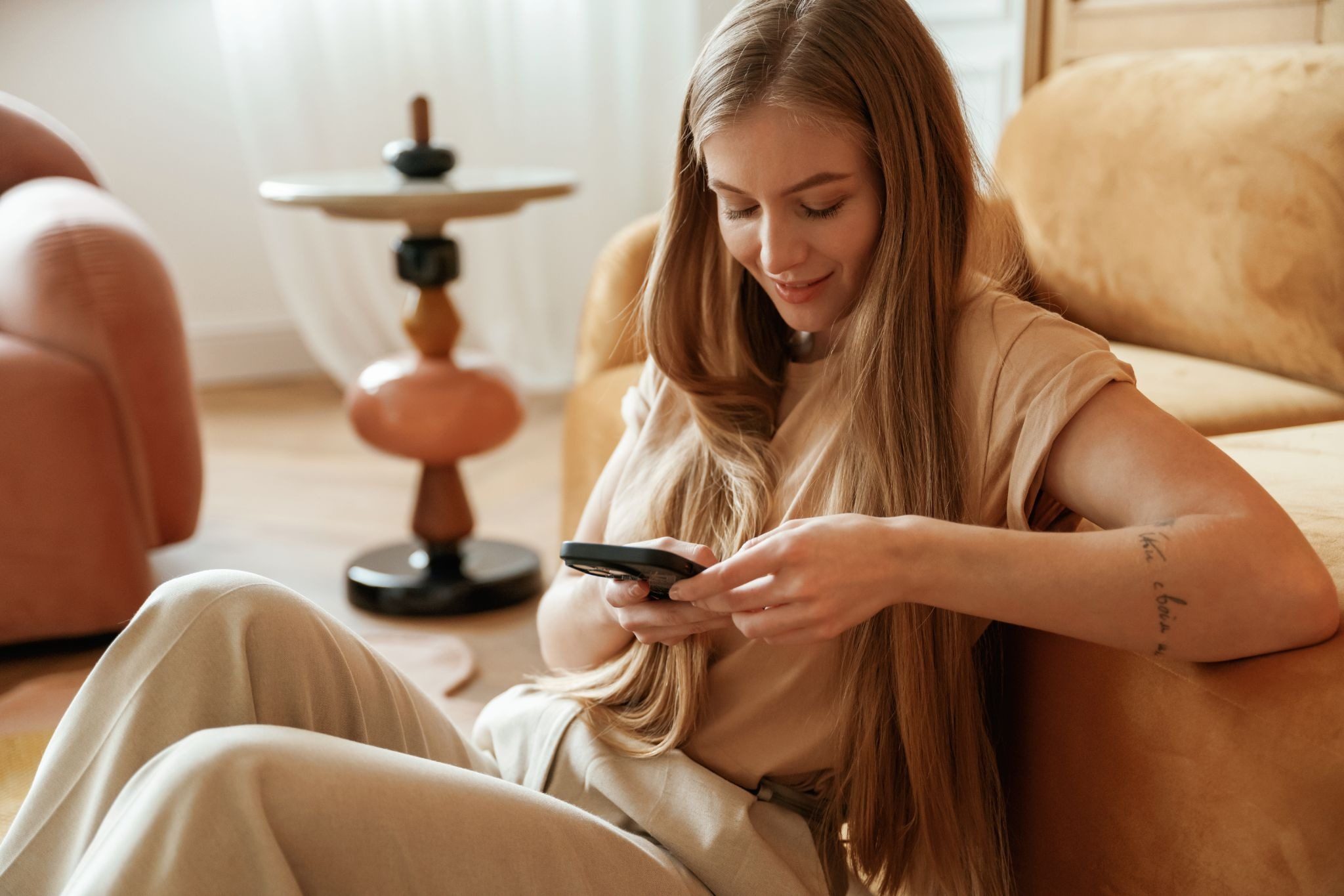 Девушка улыбается, читая новое сообщение на смартфоне